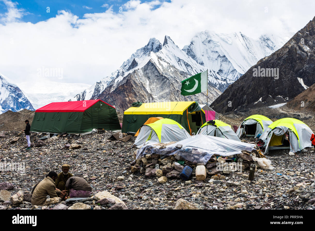 Pakistani flag in Concordia campsite with Kumul Gri (Vigne peaks) and Kondus peak in the background, Baltoro glacier, Pakistan Stock Photo