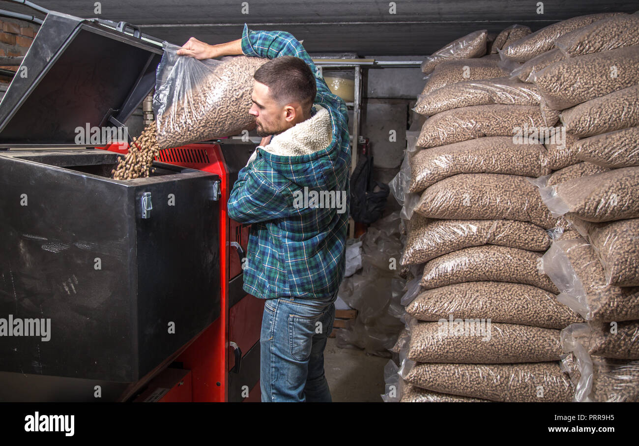 the man loads the pellets in the solid fuel boiler, working with