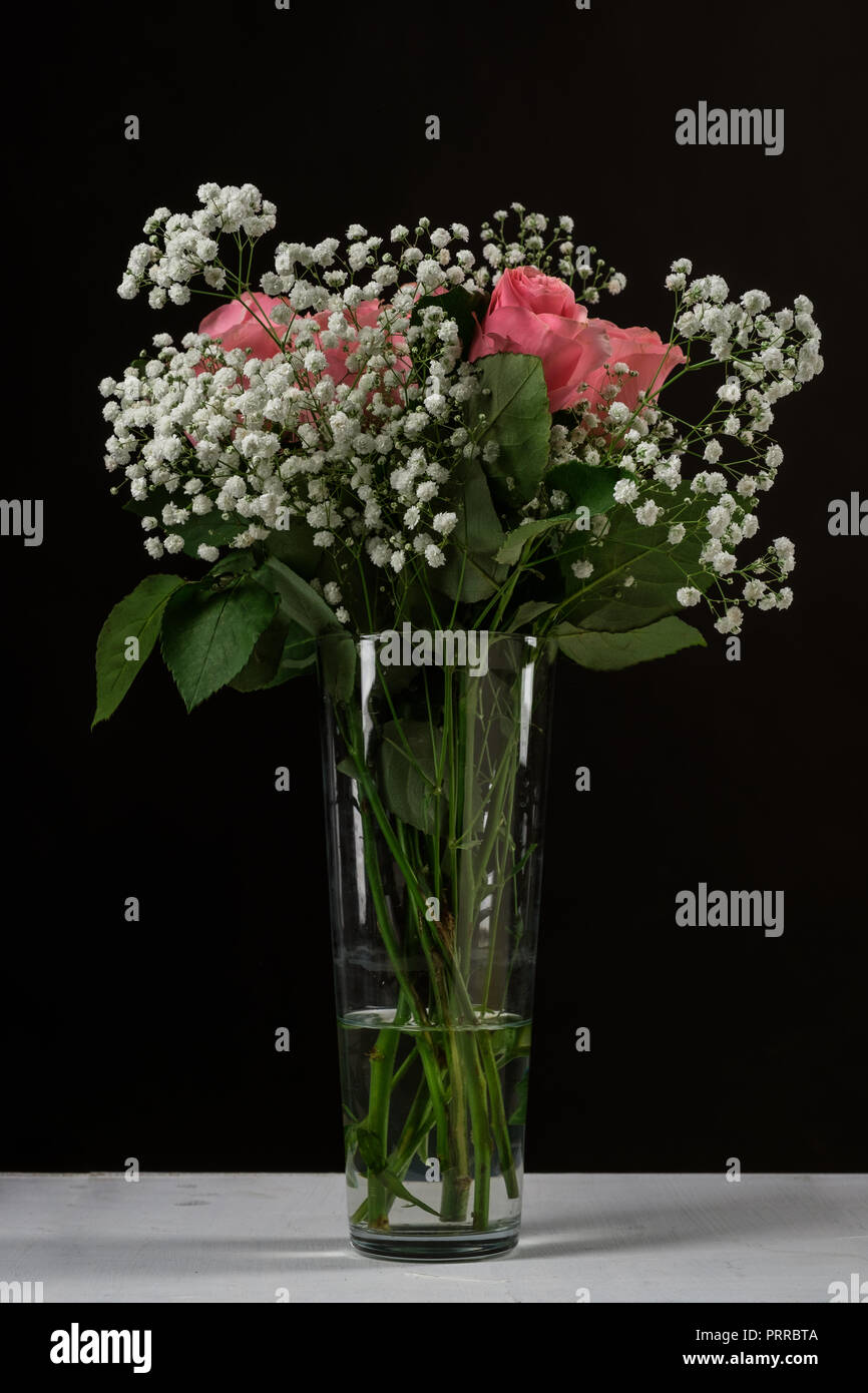 A bouquet of flowers in a glass vase on a black background Stock Photo ...