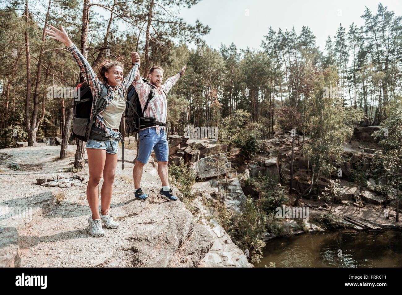 Couple of backpackers feeling extremely happy after reaching the top of rock Stock Photo