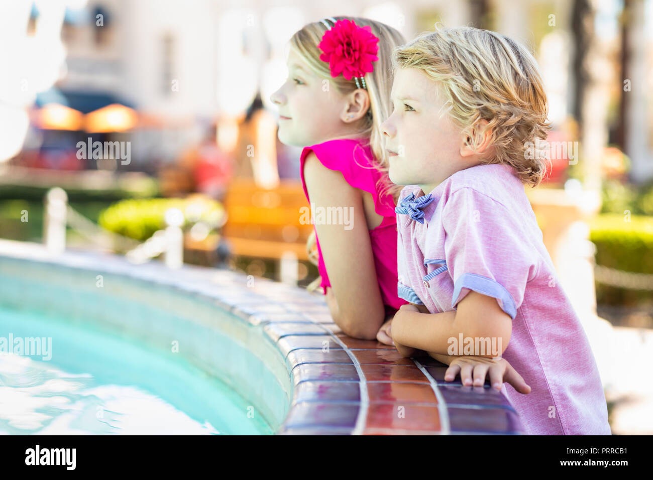 Cute Young Caucasian Brother and Sister Enjoying The Fountain At The Park. Stock Photo