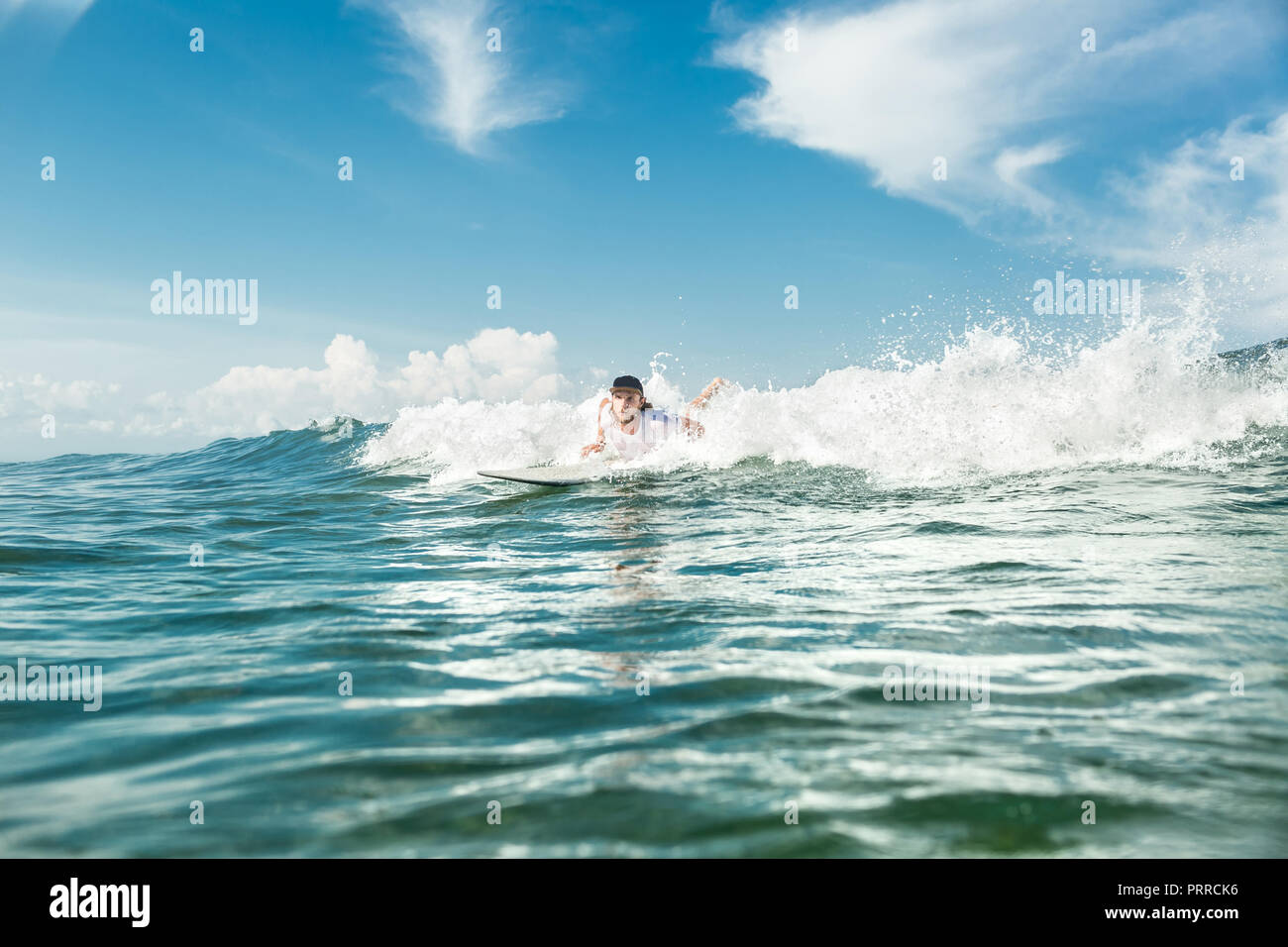 male surfer swimming on surfing board in ocean at Nusa Dua Beach, Bali, Indonesia Stock Photo