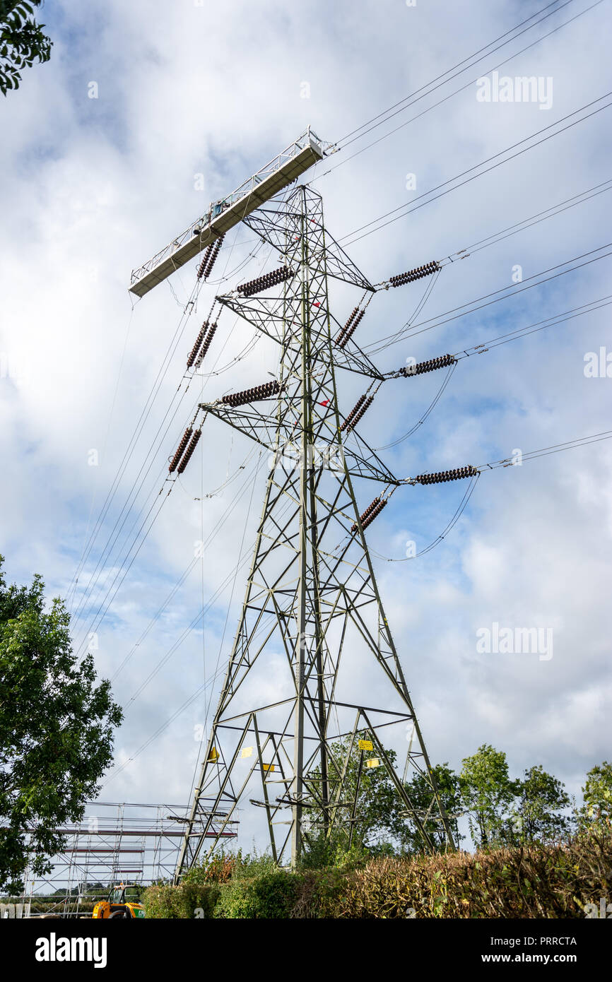 An electricity pylon with a large temporary cradle platform attached ready for workers to use when they change the high voltage cable wires Stock Photo