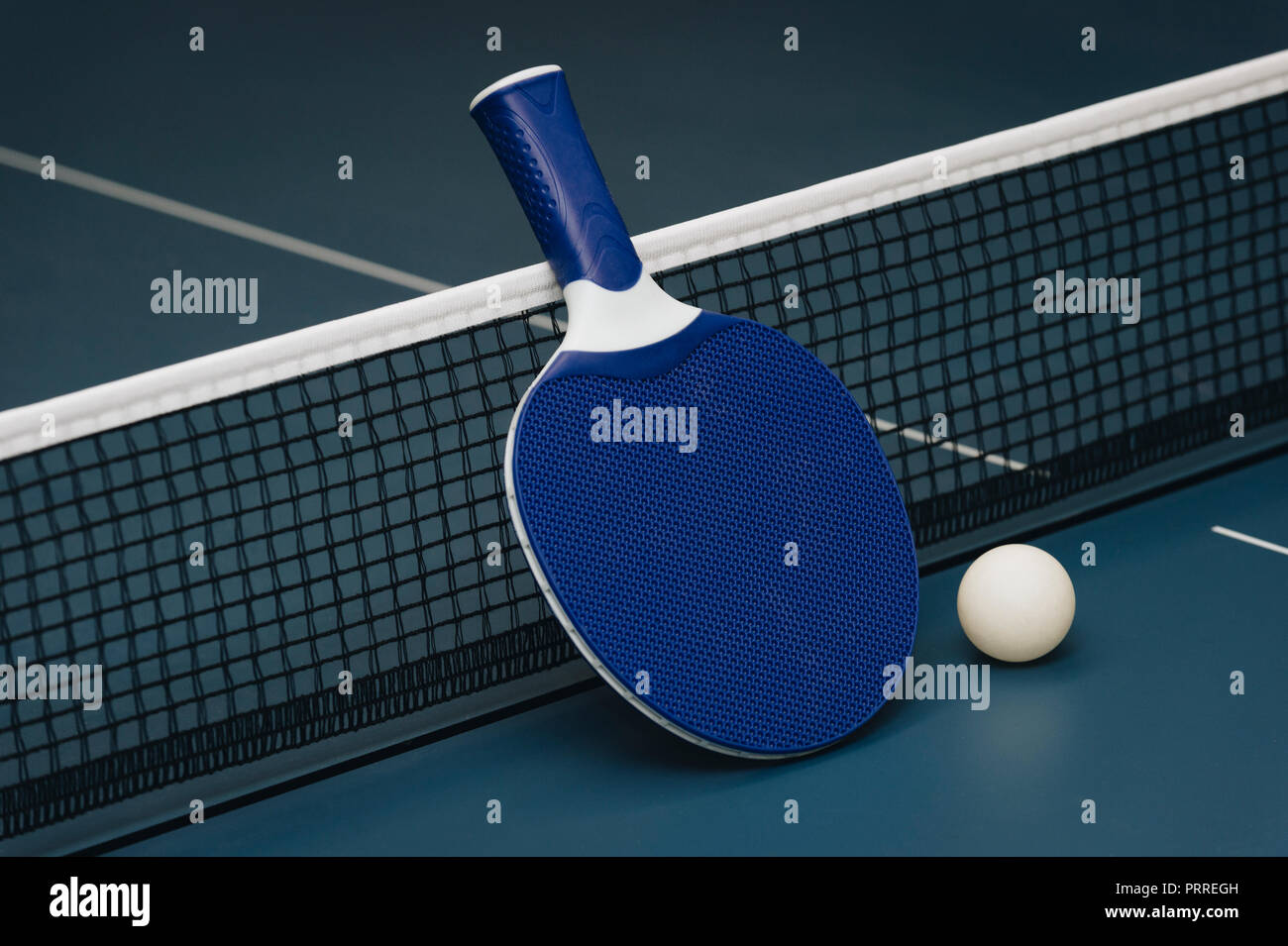 Table tennis rackets and ball and net on a blue pingpong table Stock