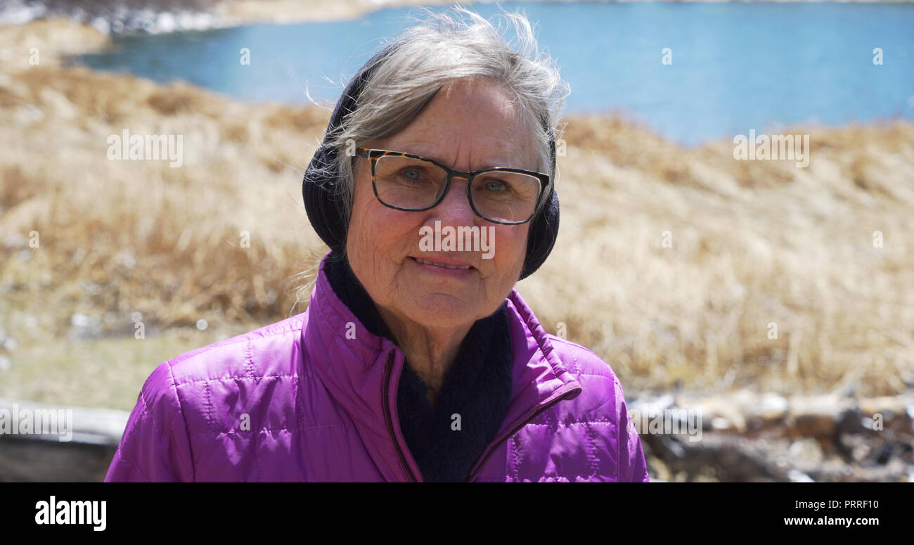 Happy elderly lady enjoying the outdoors and smiling at camera Stock Photo