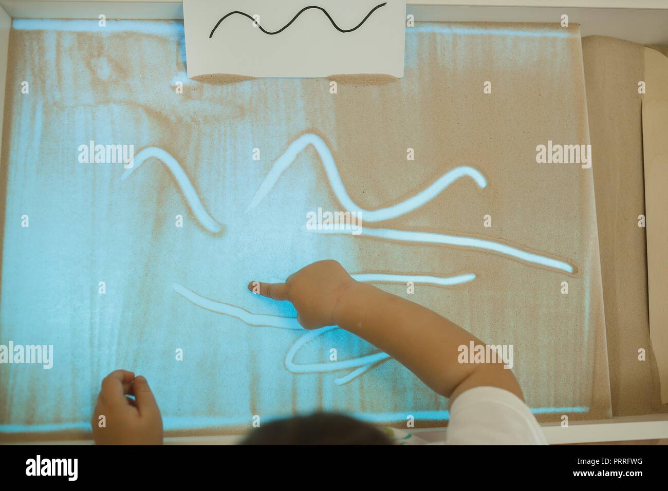 Children painting in the interactive sand box , sand animation. Educational game for toddlers. Stock Photo