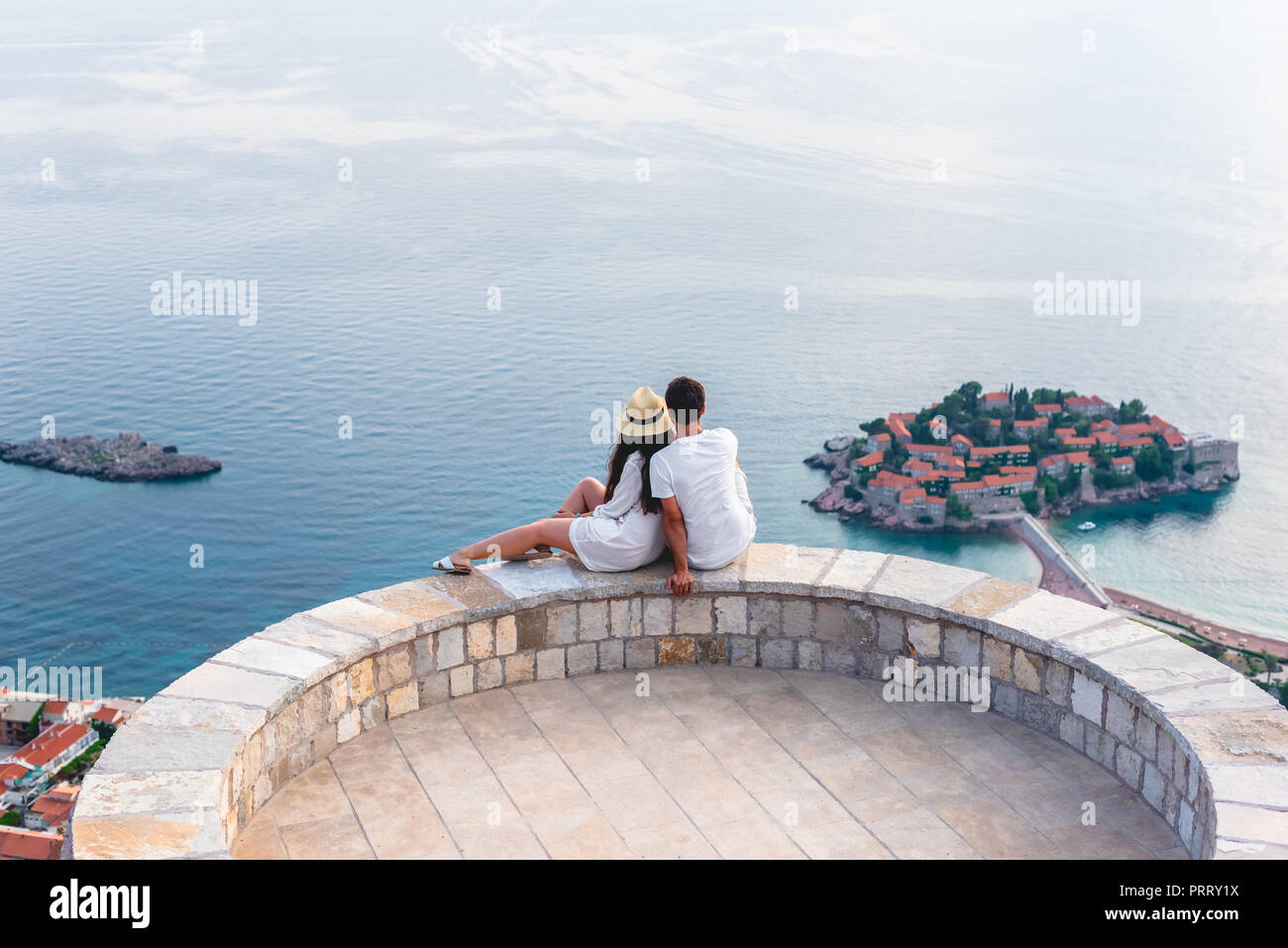 couple hugging on viewpoint and looking at island of Sveti Stefan in Budva, Montenegro Stock Photo