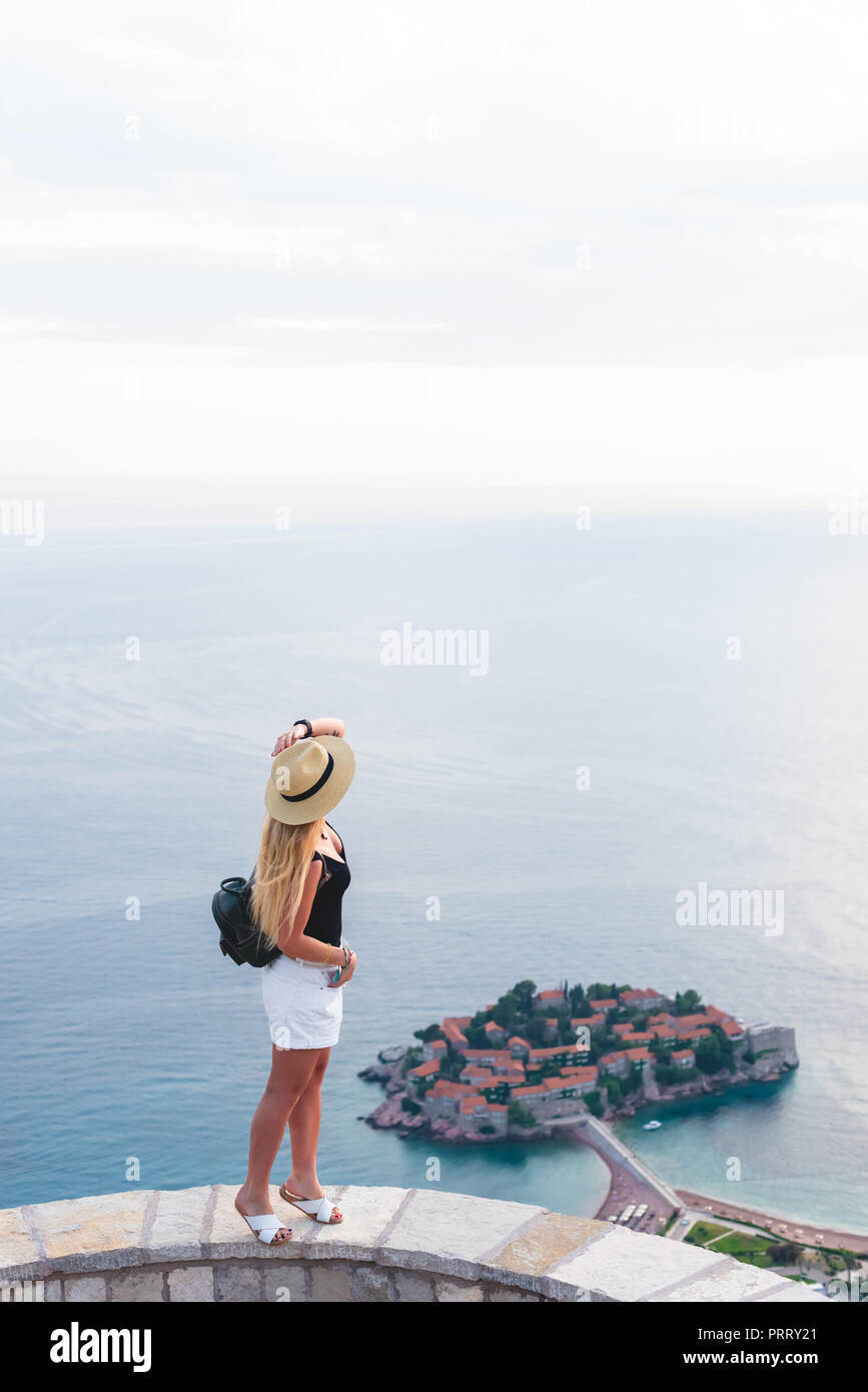 woman standing on viewpoint and looking at saint stephen island in Adriatic sea, Budva, Montenegro Stock Photo