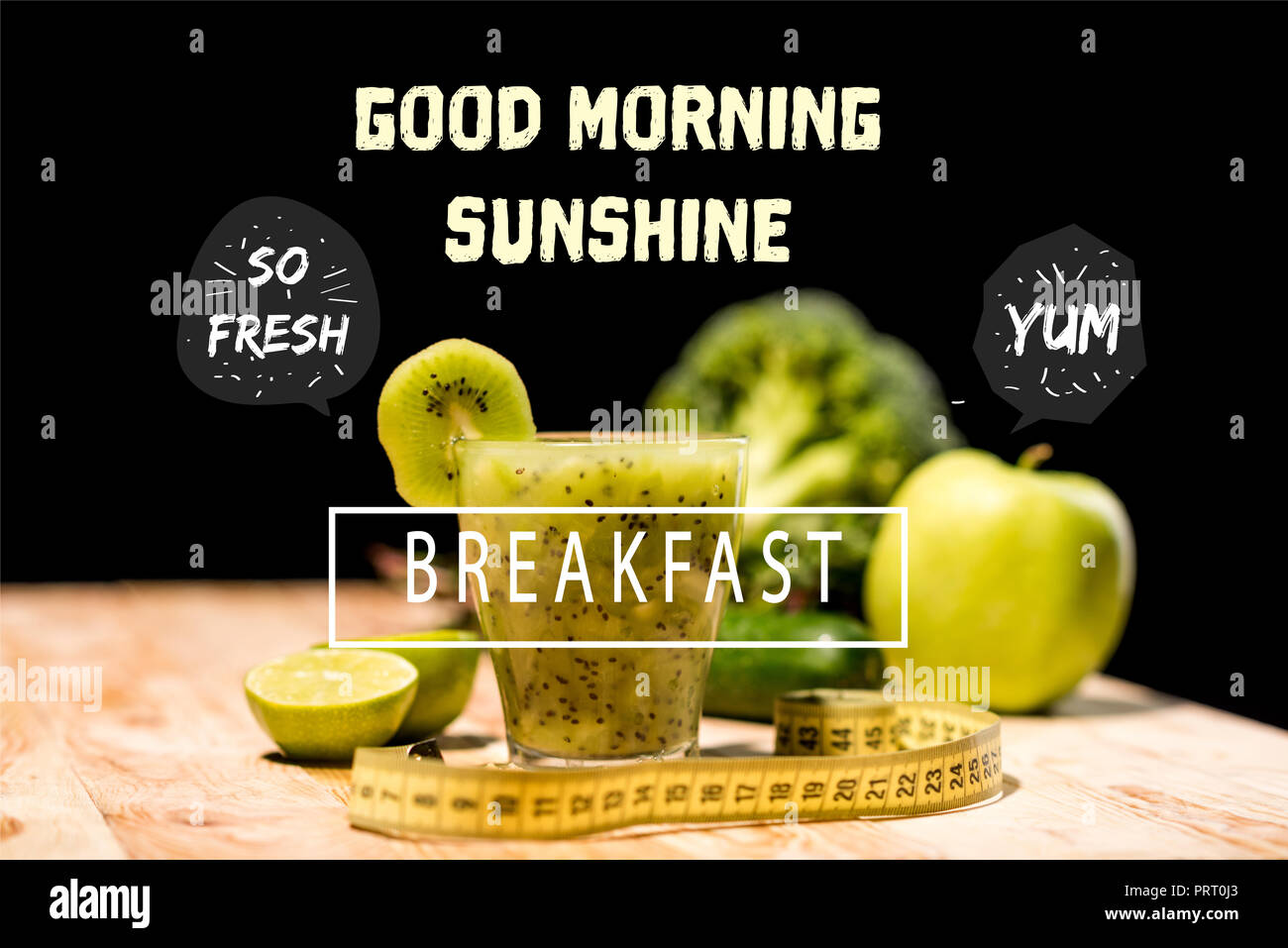 fresh fruit smoothie in glass with piece of kiwi, limes and measuring tape on tabletop, with 'good morning sunshine' and  'breakfast' letterings Stock Photo