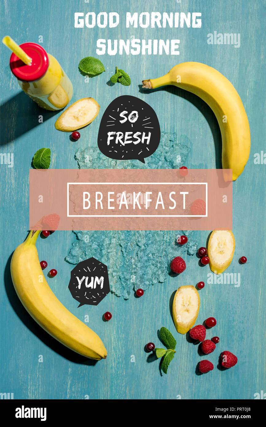 top view of bottle with fresh banana smoothie and berries with mint leaves, with 'good morning sunshine' and  'breakfast' letterings Stock Photo