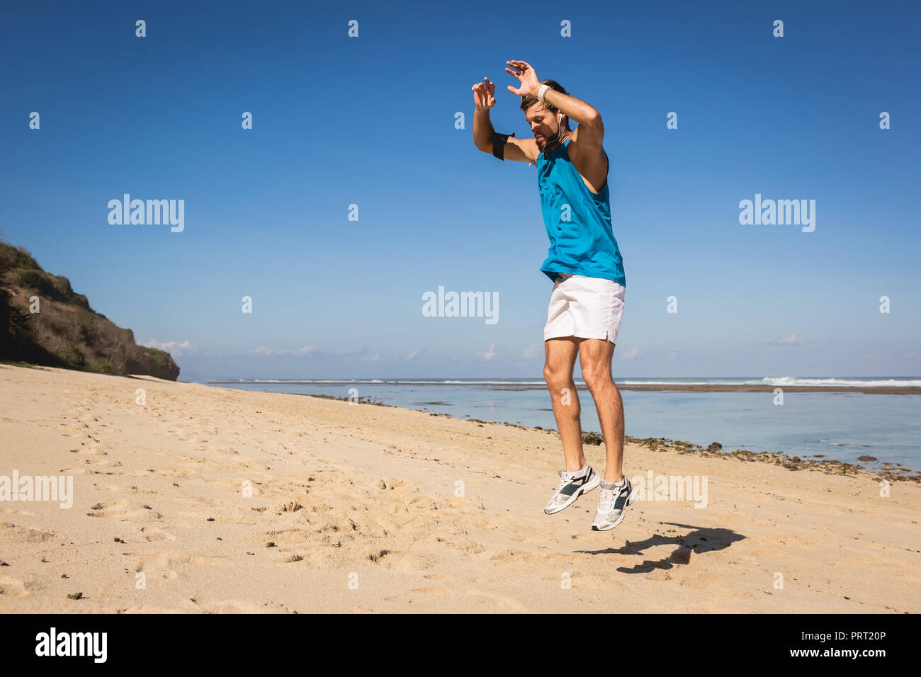 young athletic man jumping on sandy beach near sea Stock Photo