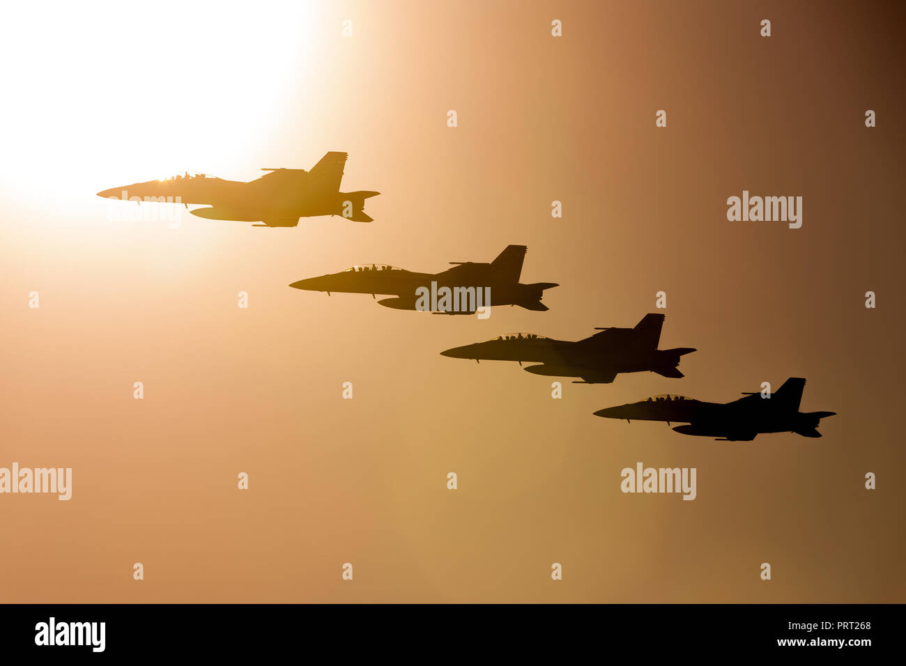 Four Royal Australian Air Force (RAAF) Boeing F/A-18F Super Hornet multirole fighter aircraft flying in formation at sunset. Stock Photo