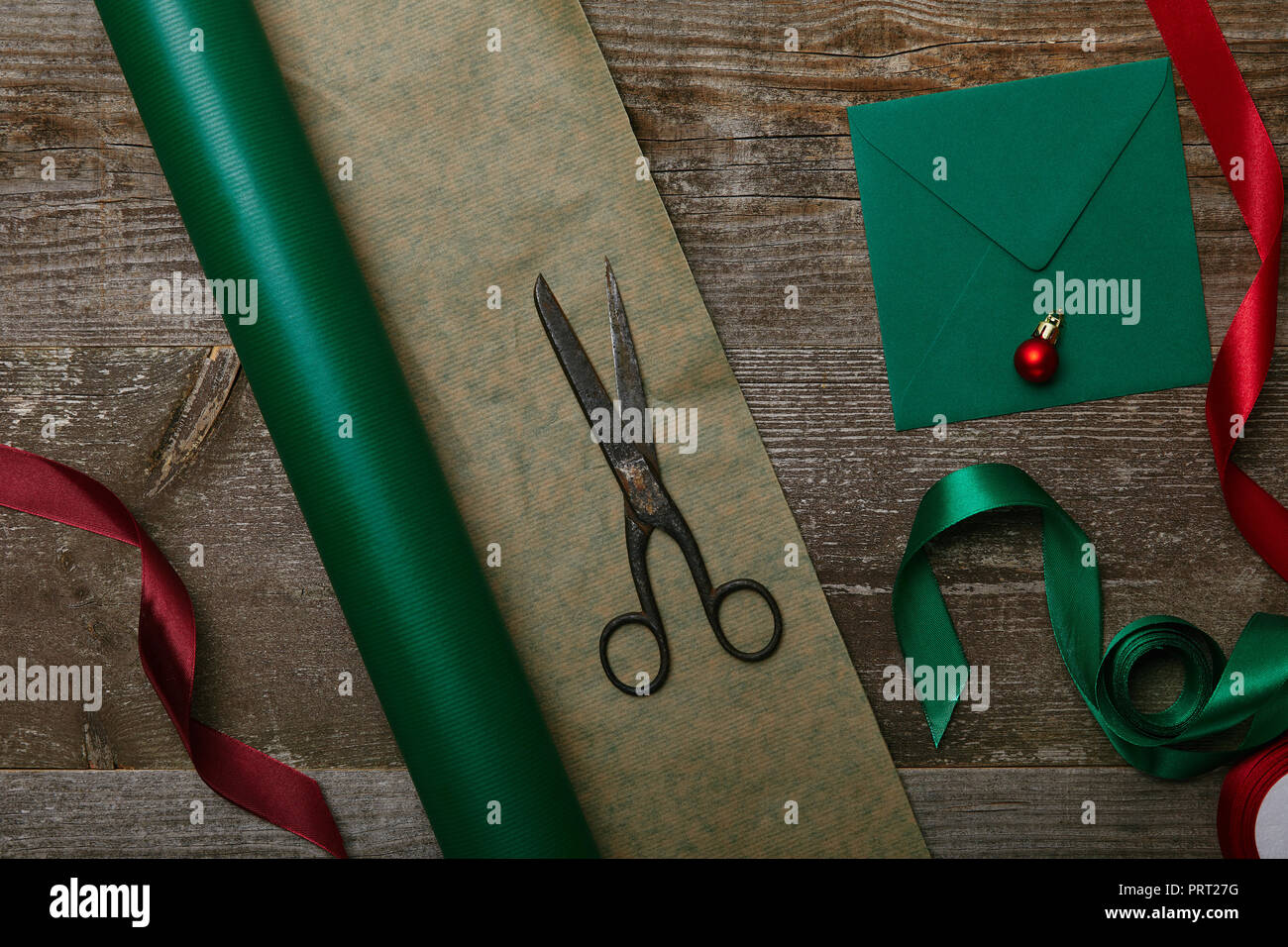 top view of green wrapping paper, scissors and present with red ribbon on  wooden background Stock Photo by LightFieldStudios