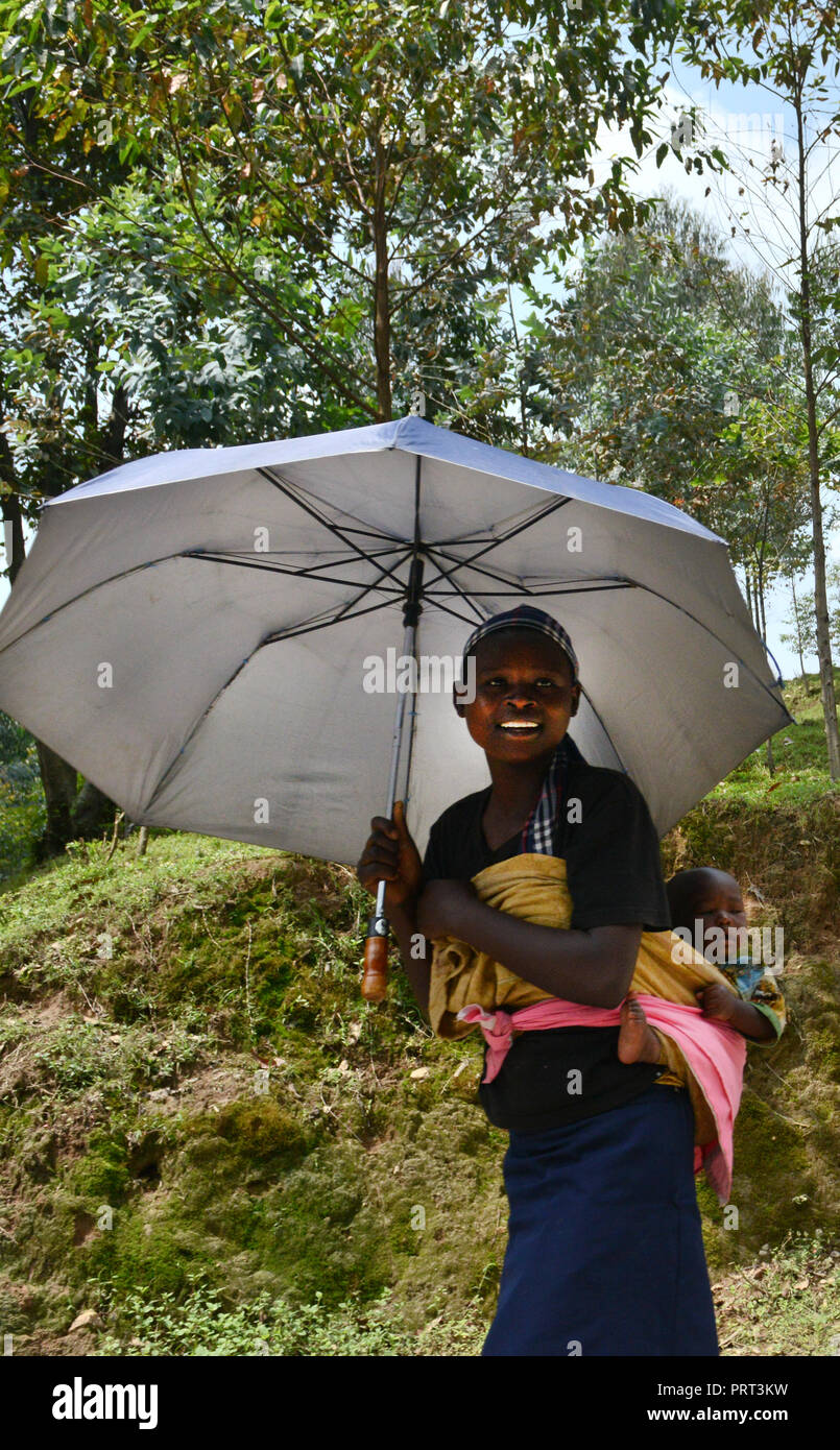 A Rwandan woman with her baby walking on a rural road in western Rwanda ...