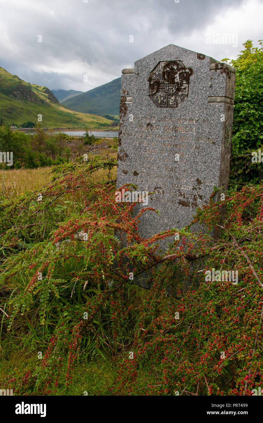 Single large commemorative grave stone on land over looked by hills and water in the Scottish Highlands. Stock Photo