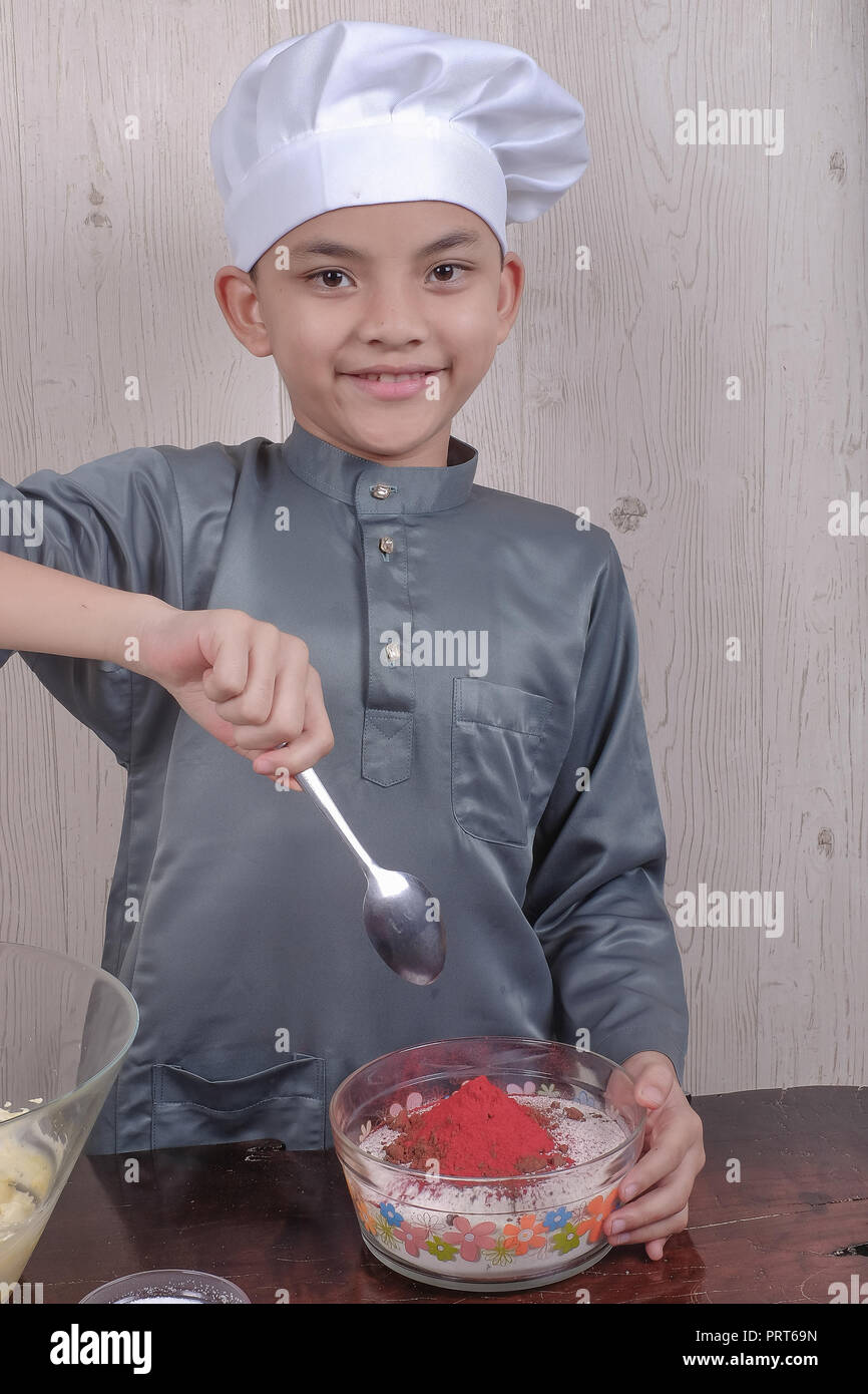 Happy boy mixing ingradients in the glass bowl and preparing a red