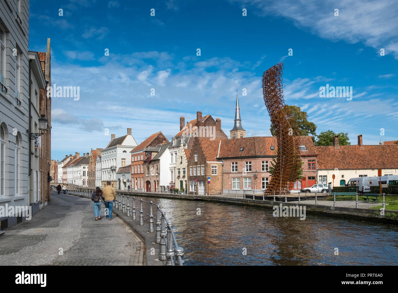 Modern metal street art displayed alongside a canal with traditional architecture in the medieval city of Bruges, West Flanders, Belgium. Stock Photo