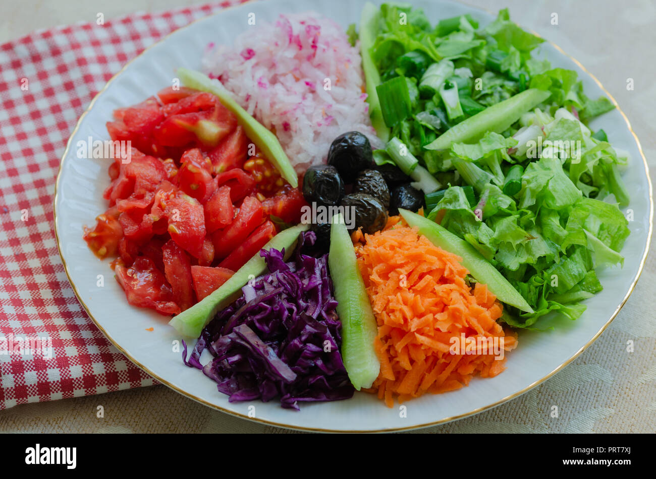 Fresh mixed vegetables salad. Selective focus,top view.There are tomatoes, lettuce, onions, radishes, carrots, purple cabbage, olives and cucumbers. Stock Photo