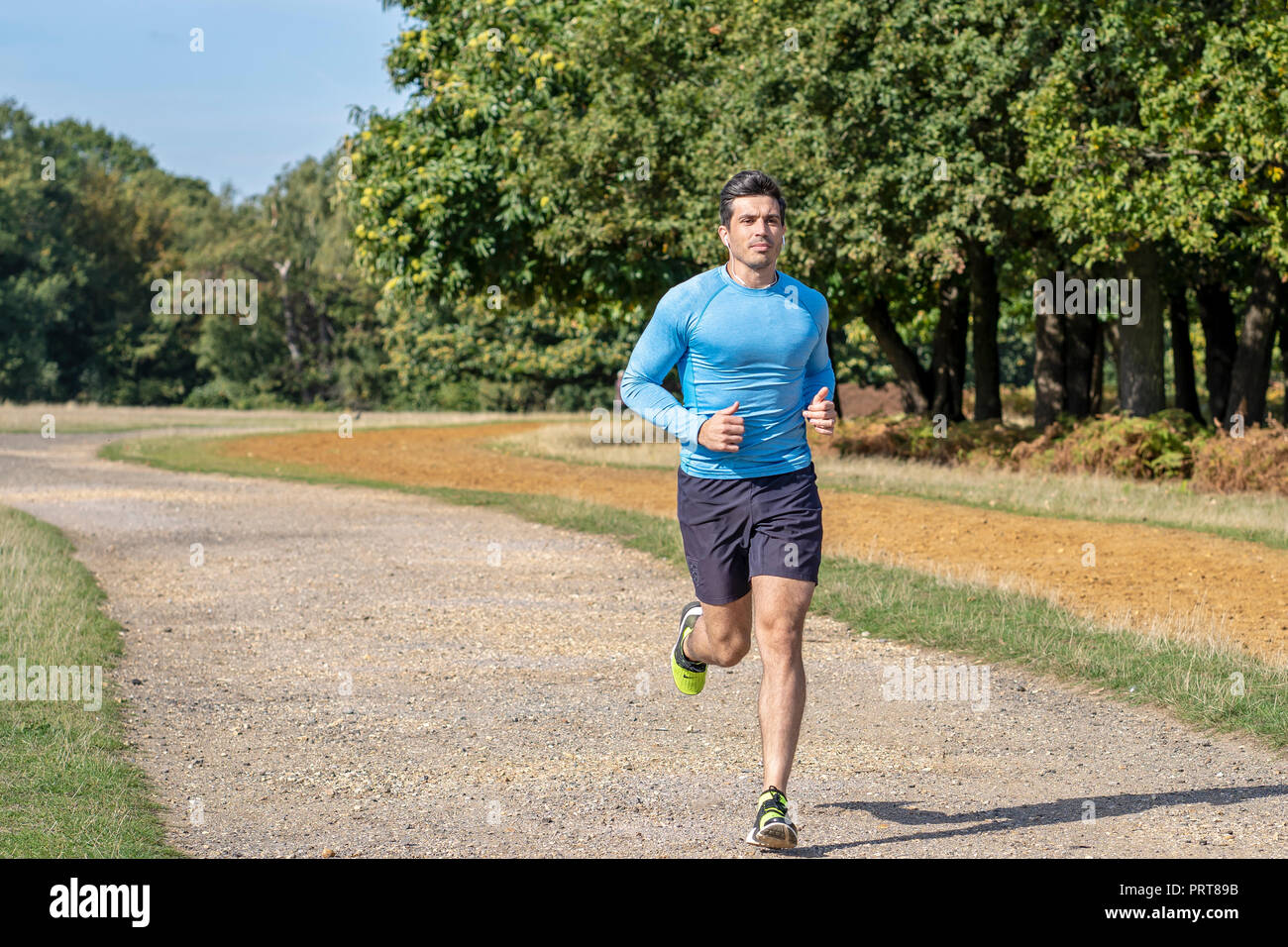 Attractive Man Jogging in the Park. Personal Trainer running and doing Exercise Stock Photo