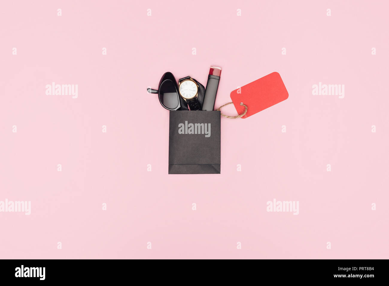 top view of little shopping bag with lipstick, accessories and empty sale tag isolated on pink Stock Photo
