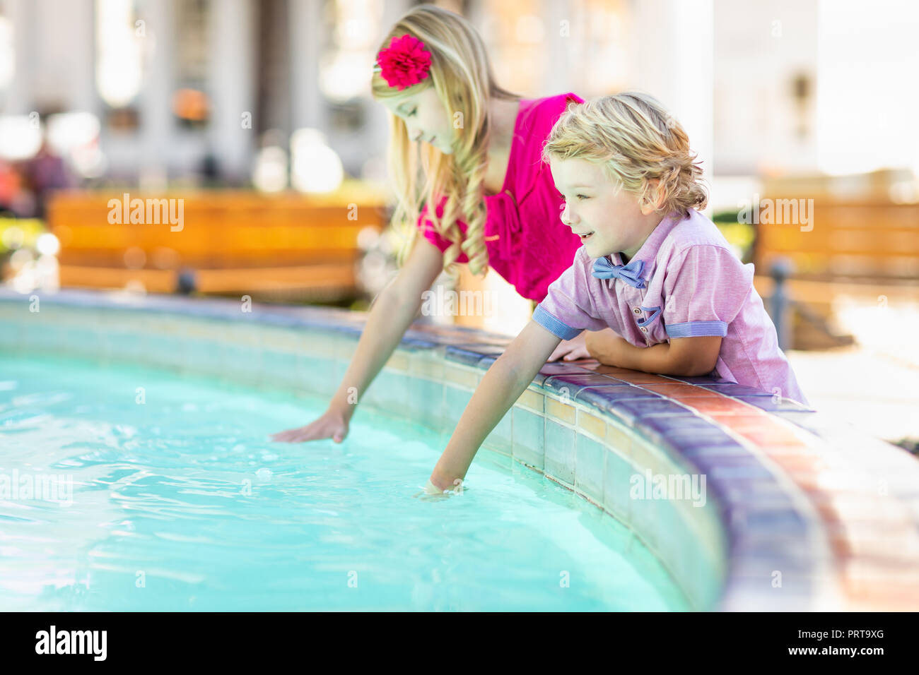 Cute Young Caucasian Brother and Sister Enjoying The Fountain At The Park. Stock Photo