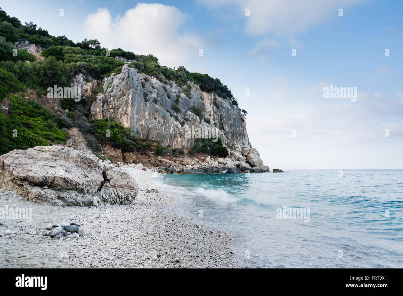 Cala Gonone beach in Sardinia with rocks  on an overcast summer day, perfect vacation place. Seascape view. Stock Photo