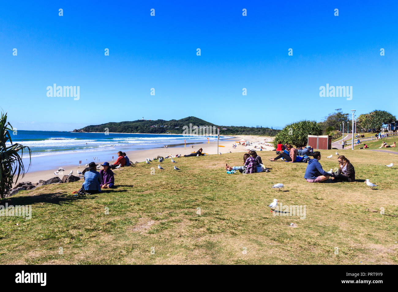 Byron Bay, Australia - 14th May 2015: People sitting on grass at the beach. The area is popular with young people. Stock Photo