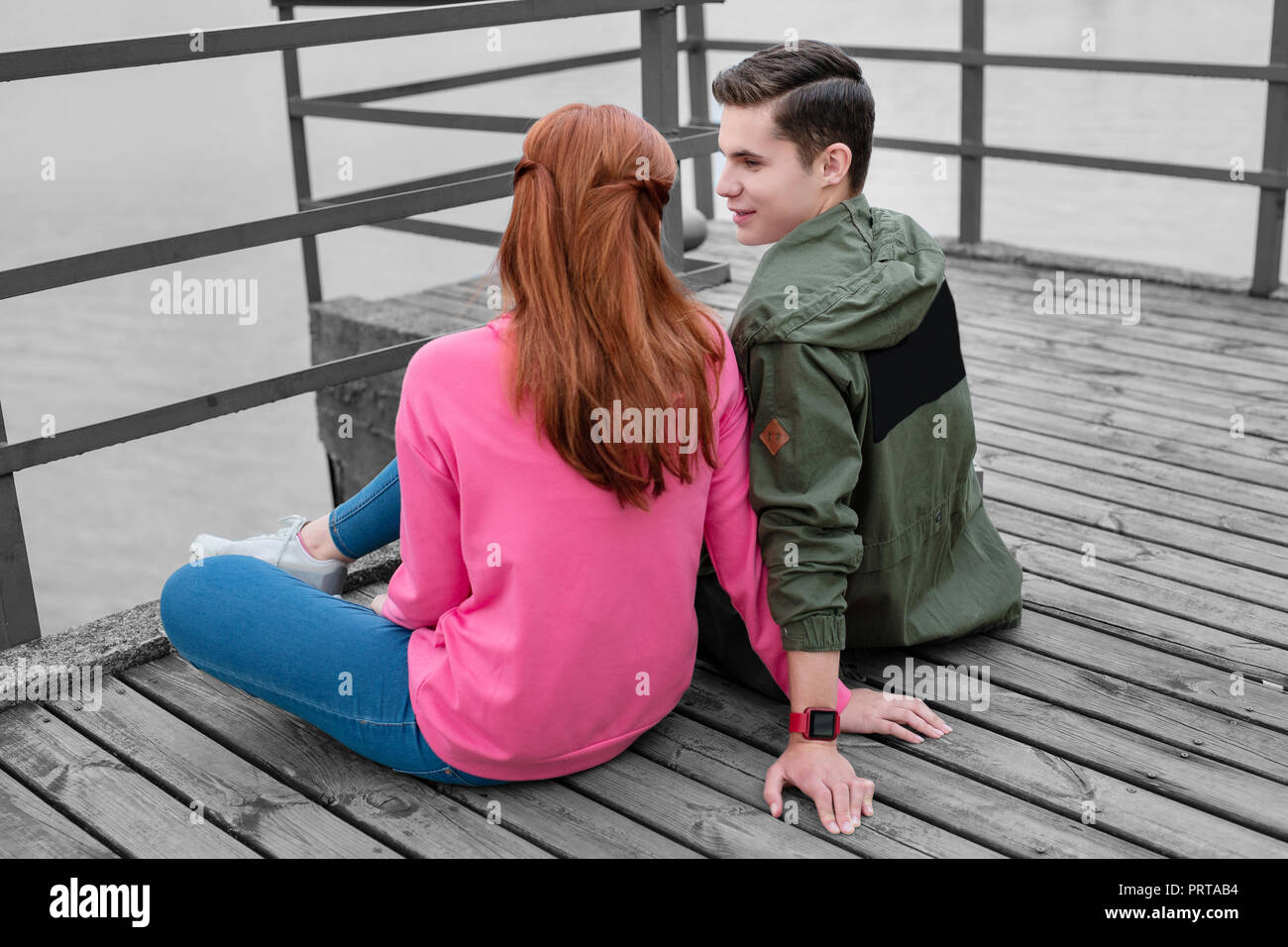 Emotional boy looking at his girlfriend while talking to her Stock Photo