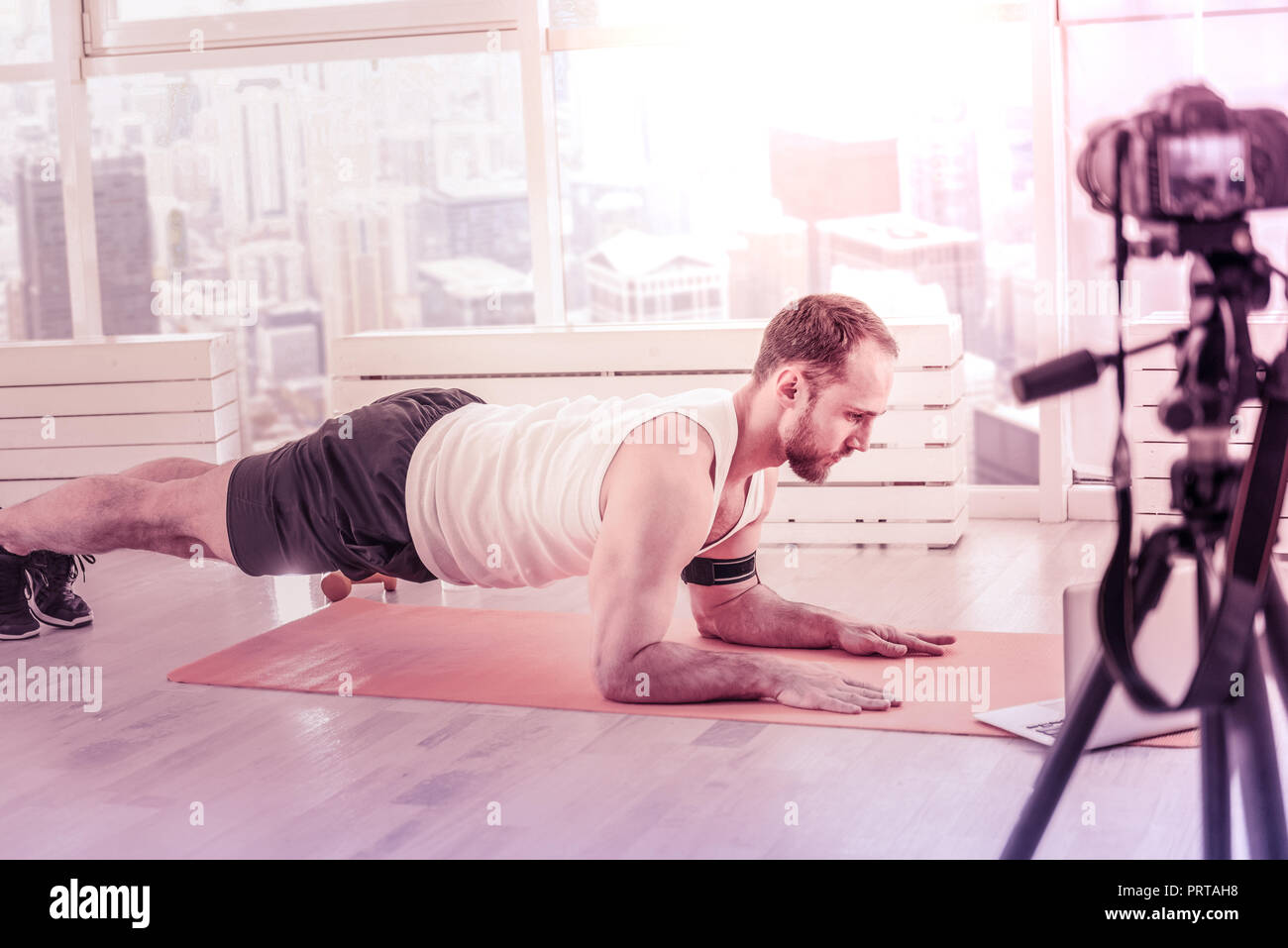 Concentrated trainer doing pushup tutorials at home Stock Photo - Alamy