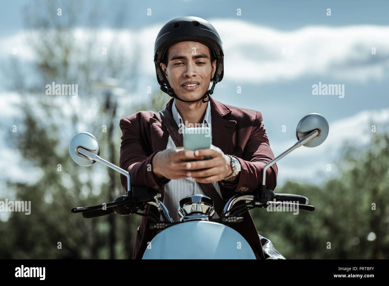 Serious pleasant guy surfing Internet on motorbike Stock Photo