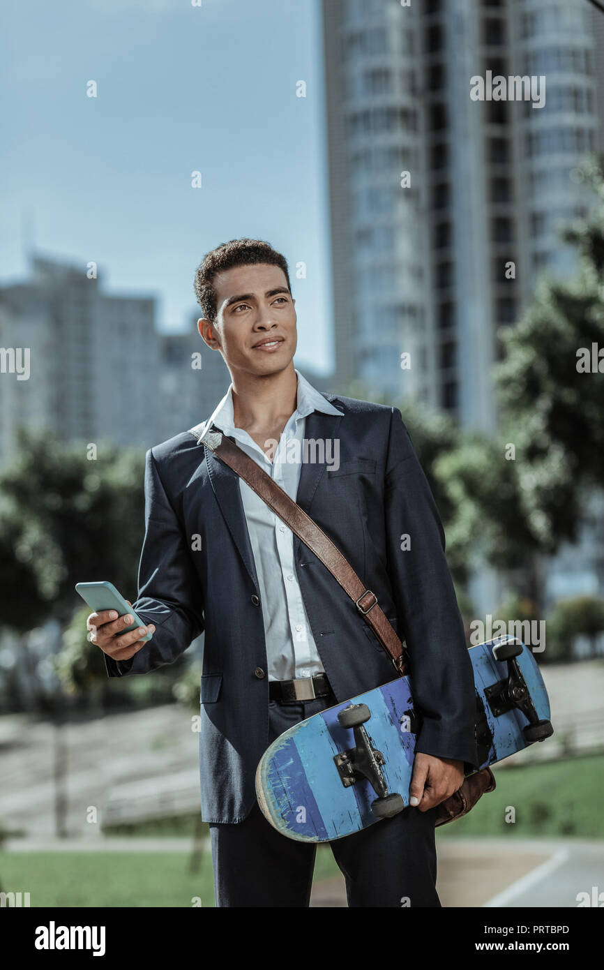 Active male student answering phone with skateboard Stock Photo