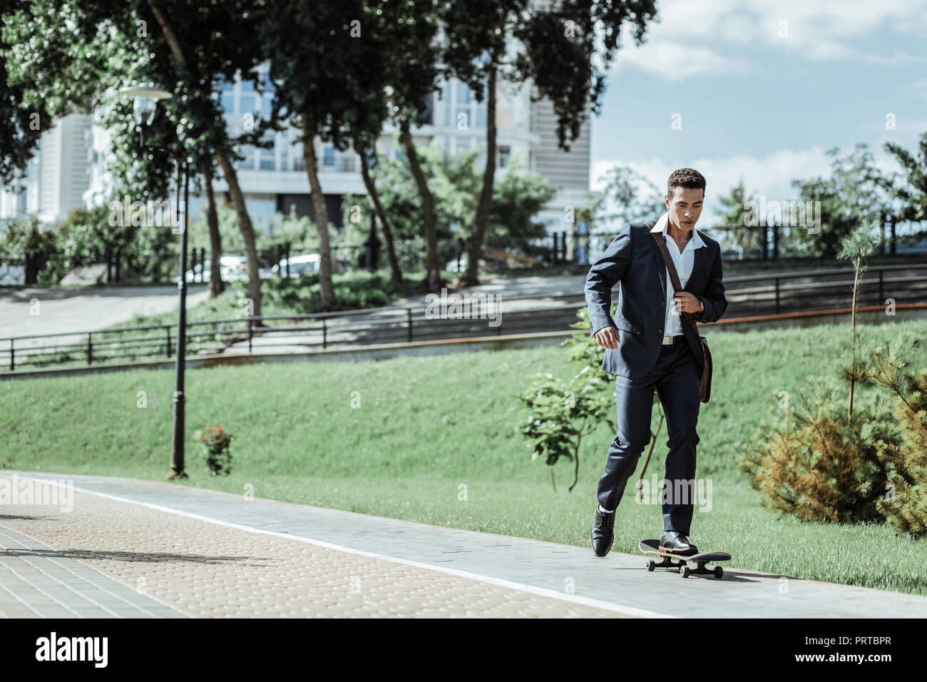 Young male student practicing riding on skateboard Stock Photo