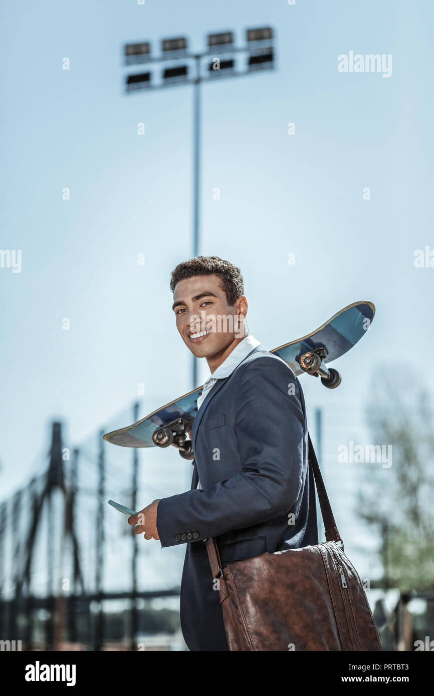 Positive male student skateboarding with his friends Stock Photo