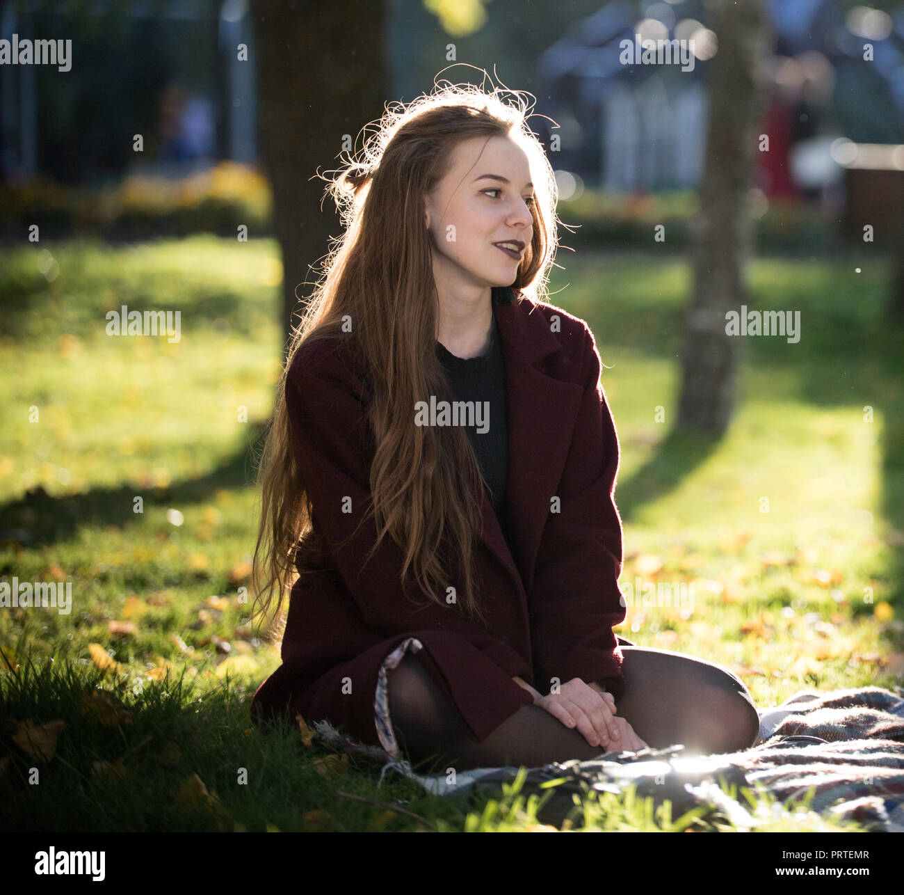 Beautiful Long Haired Girl Sits On A Plaid In The Autumn Park And