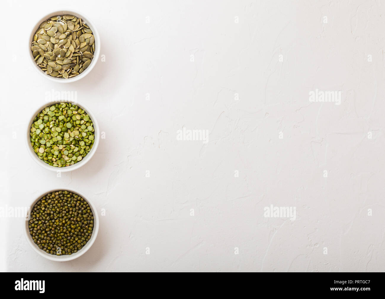 Bowl of mung beans and split peas and pumkin seeds on white kitchen