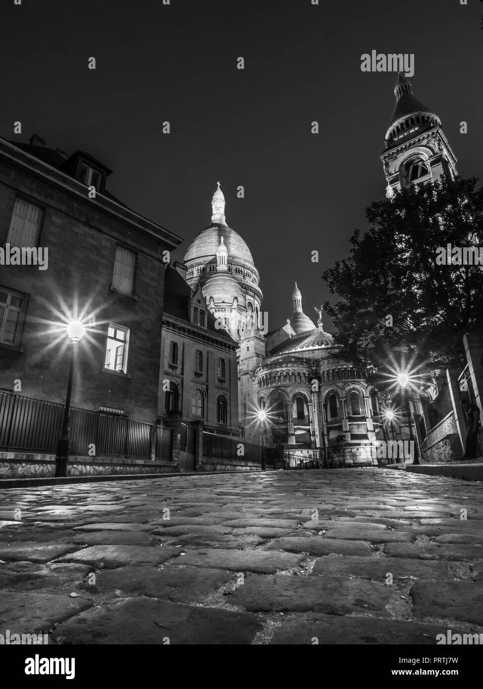 The early eving glow from street lamps on a cobbled street near to ther basilica of Sacre Couer in Montmartre district of Paris Stock Photo