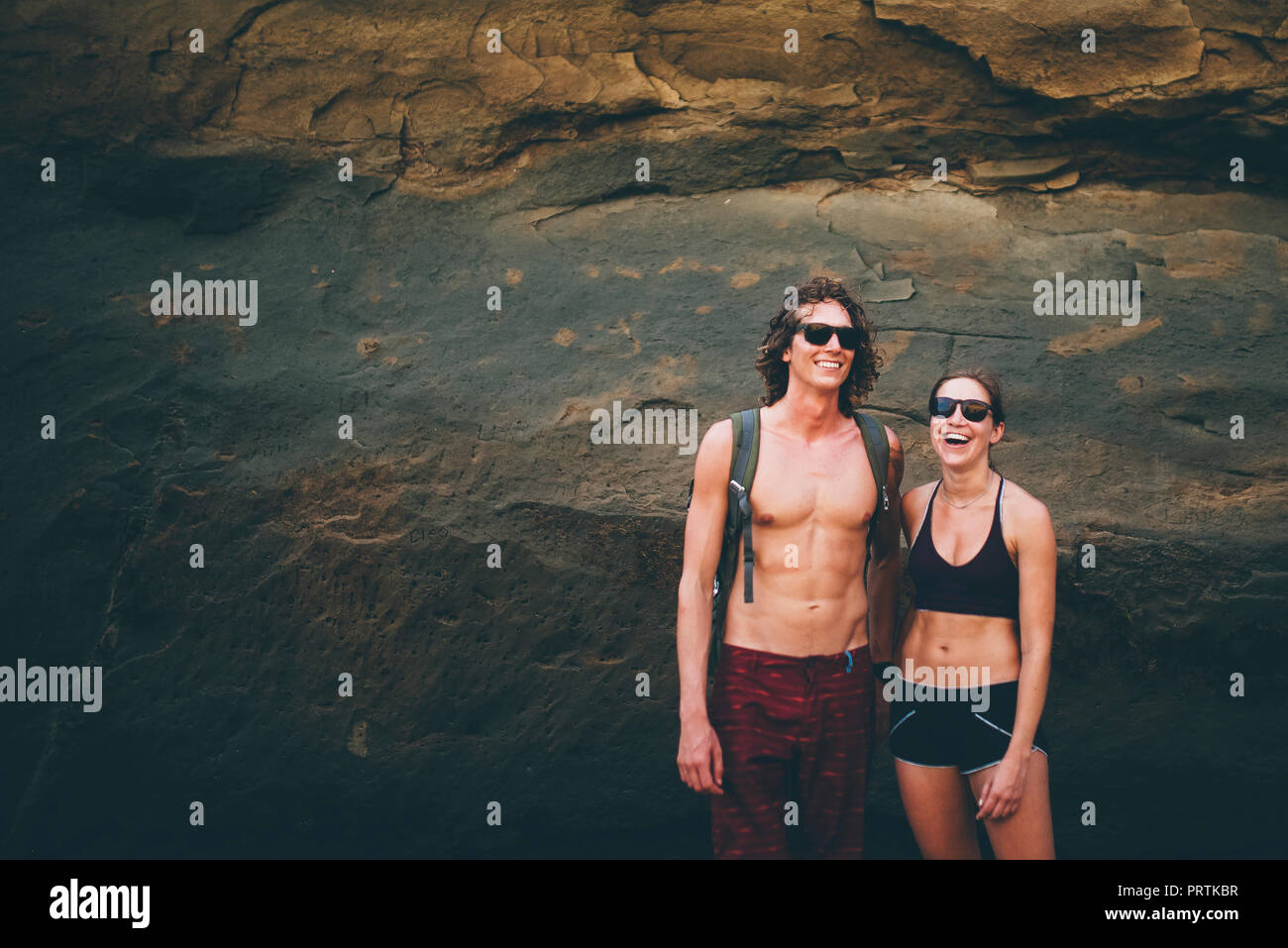 Couple posing against rock face, Canoa, Manabi, Ecuador Stock Photo