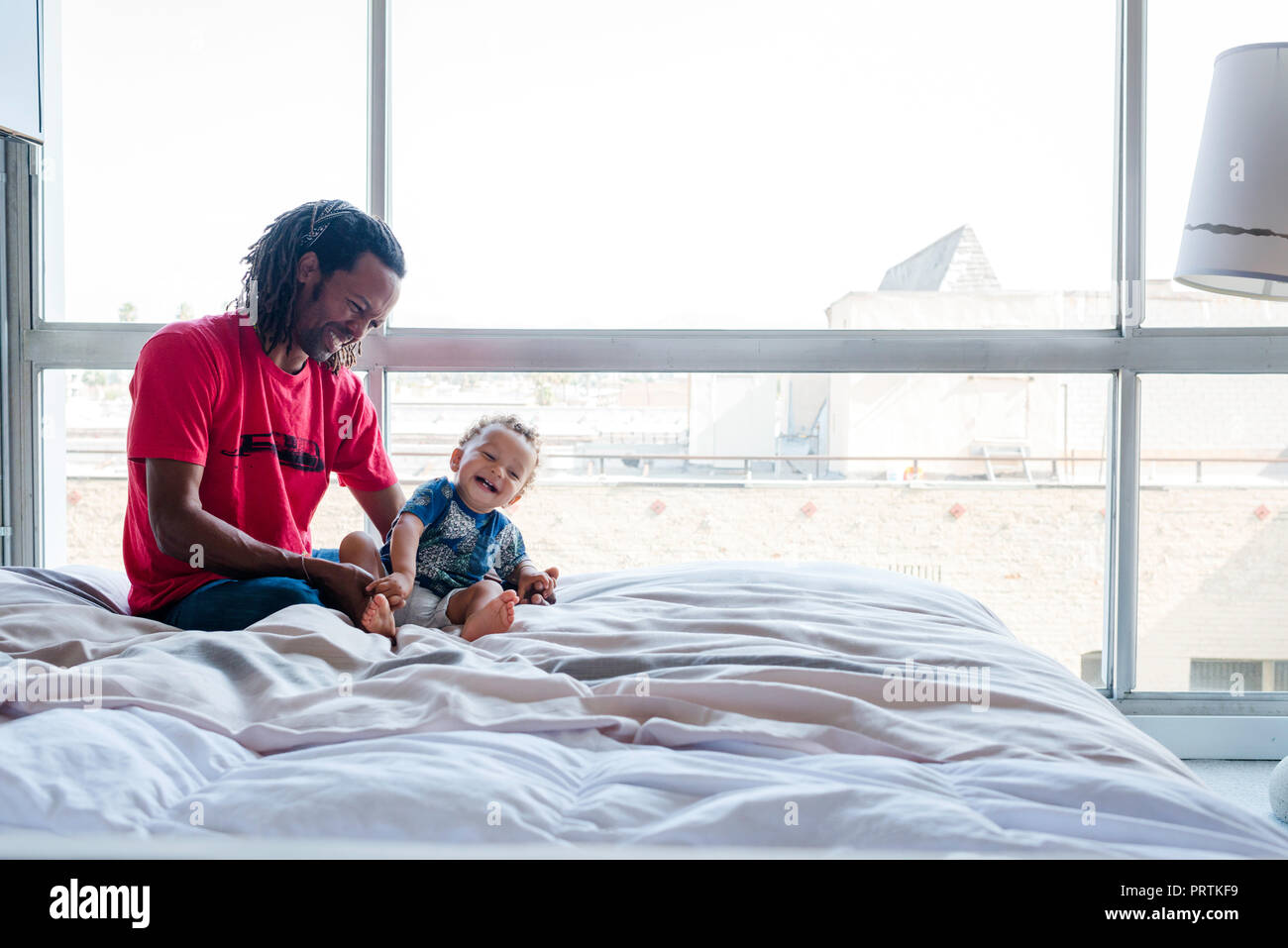 Father and son playing on bed Stock Photo