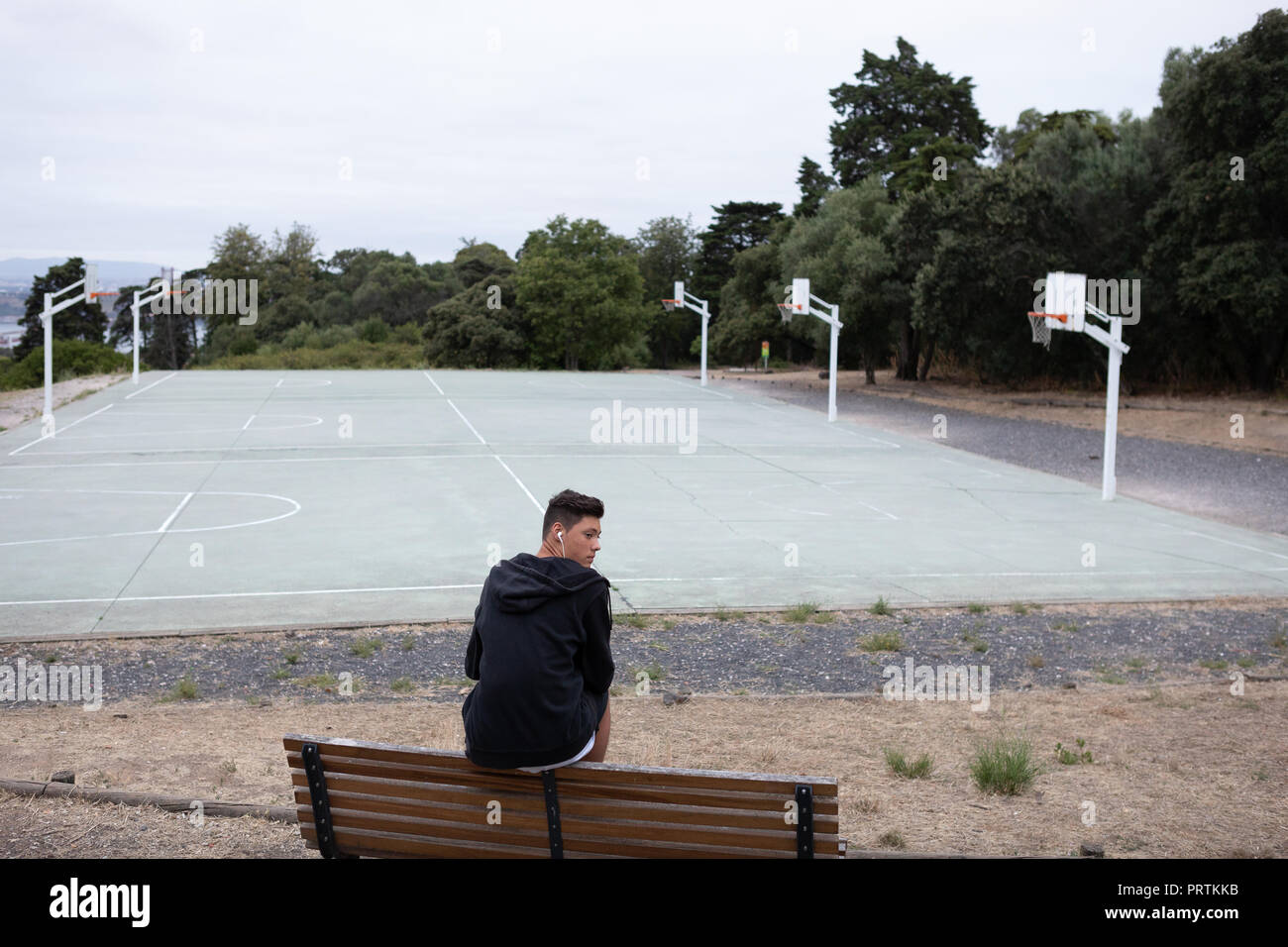 Male teenage basketball player looking back from park bench by basketball  court Stock Photo - Alamy