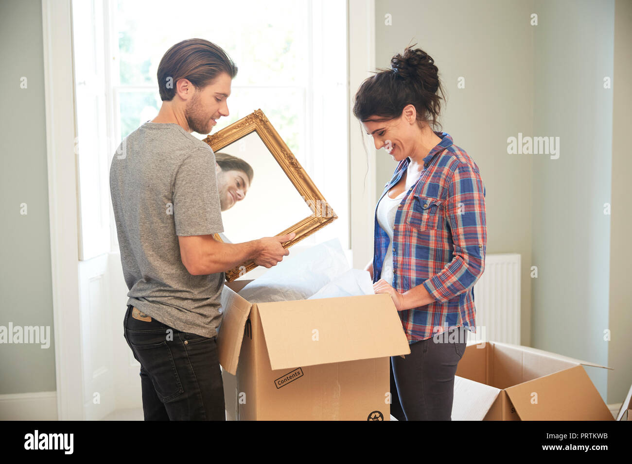 Couple packing mirror into cardboard box Stock Photo