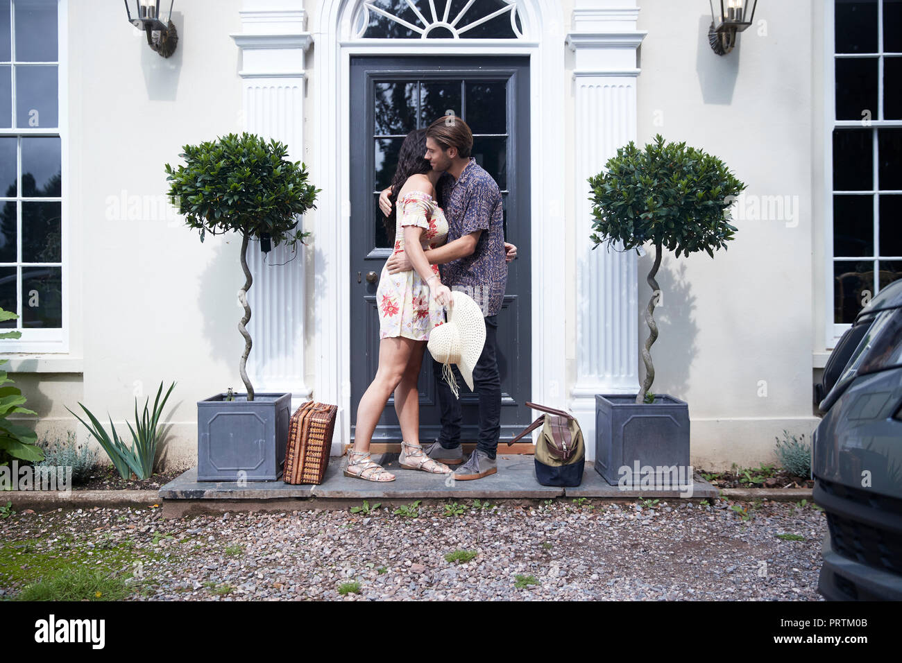 Romantic couple hugging each other at hotel front door Stock Photo