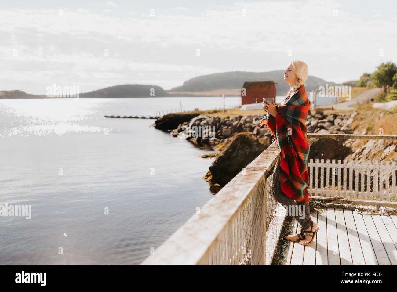 Woman enjoying morning drink on balcony by sea, Halifax, Canada Stock Photo