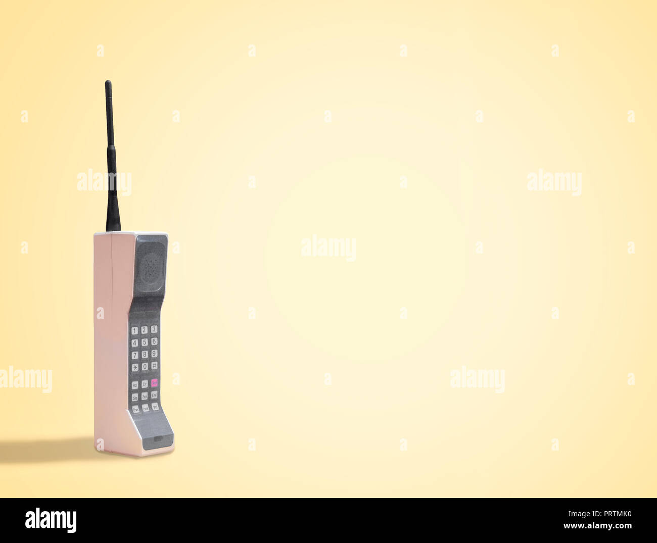 Retro mobile cell phone on a vintage yellow background with space for copy and text Stock Photo