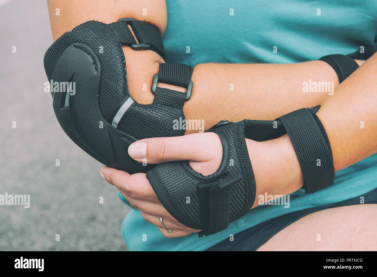 Woman rollerskater with elbow protector pads on her hand and wearing wrist guards Stock Photo