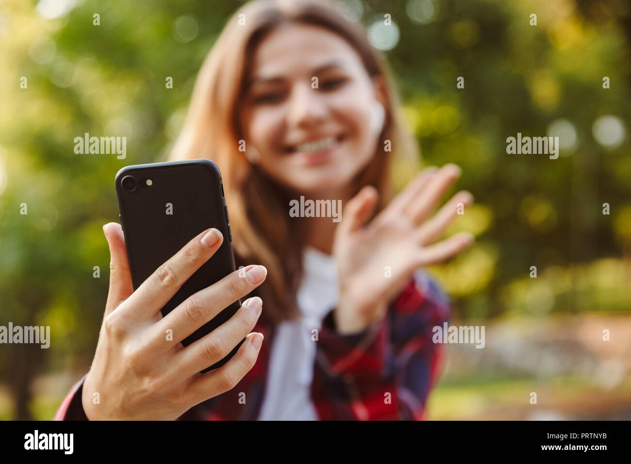 Image of young beautiful woman student walking outdoors talking by mobile phone waving. Stock Photo