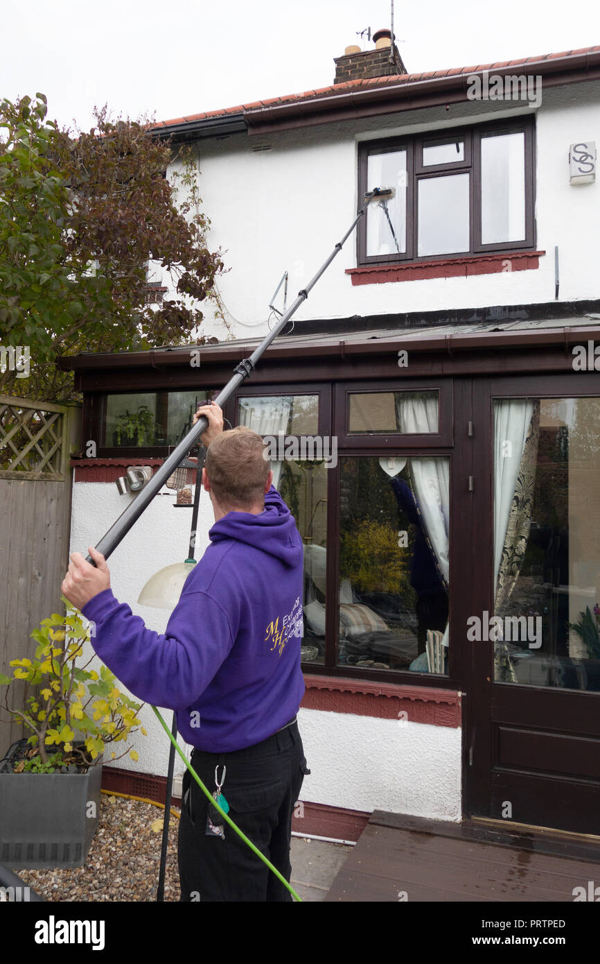 Window Cleaner using the ‘reach and wash’ system (waterfed pole and filtration system Stock