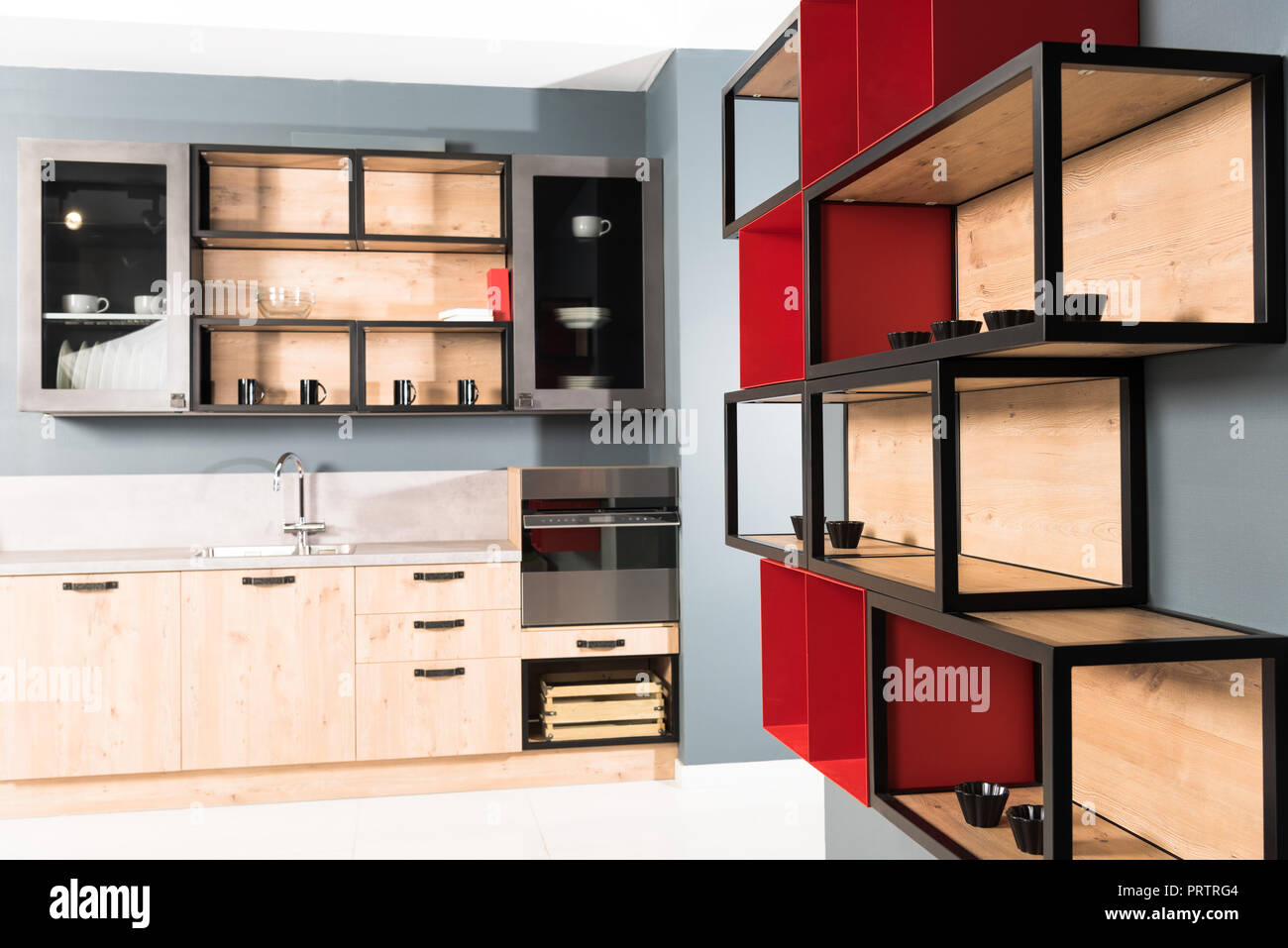 interior of modern clean light kitchen with kitchen counters and red shelves Stock Photo