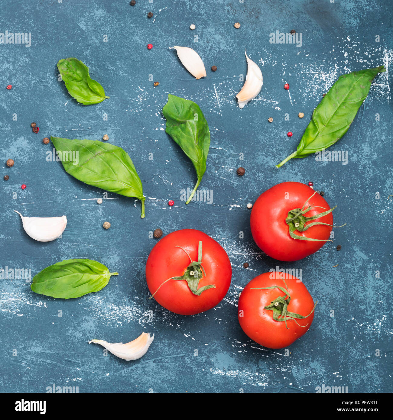 Cooking  ingredients - basil leaves,garlic cloves, pepper and tomatoes. Concrete grunge background. Top view. Square image Stock Photo