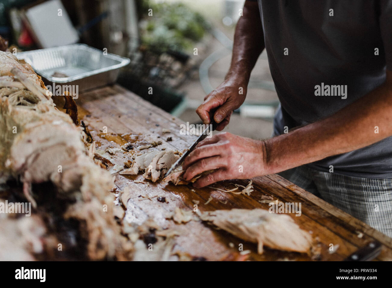 Man slicing hog roast on table, cropped Stock Photo