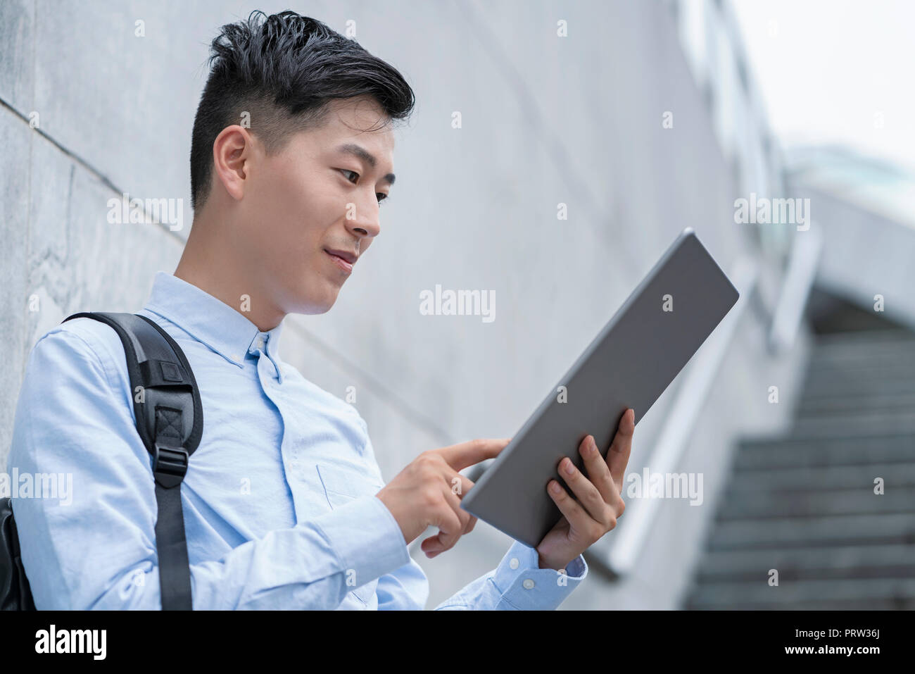 Young businessman using digital tablet on city stairway, Shanghai, China Stock Photo